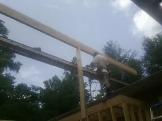 Carpenter setting a ridge beam over a new addition frame — Ice Dam Removal by Roofing Brothers in Lewes