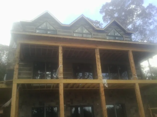 Dormers and porch framing on a large log home under construction — Roof Coating work by our crew in Lewes