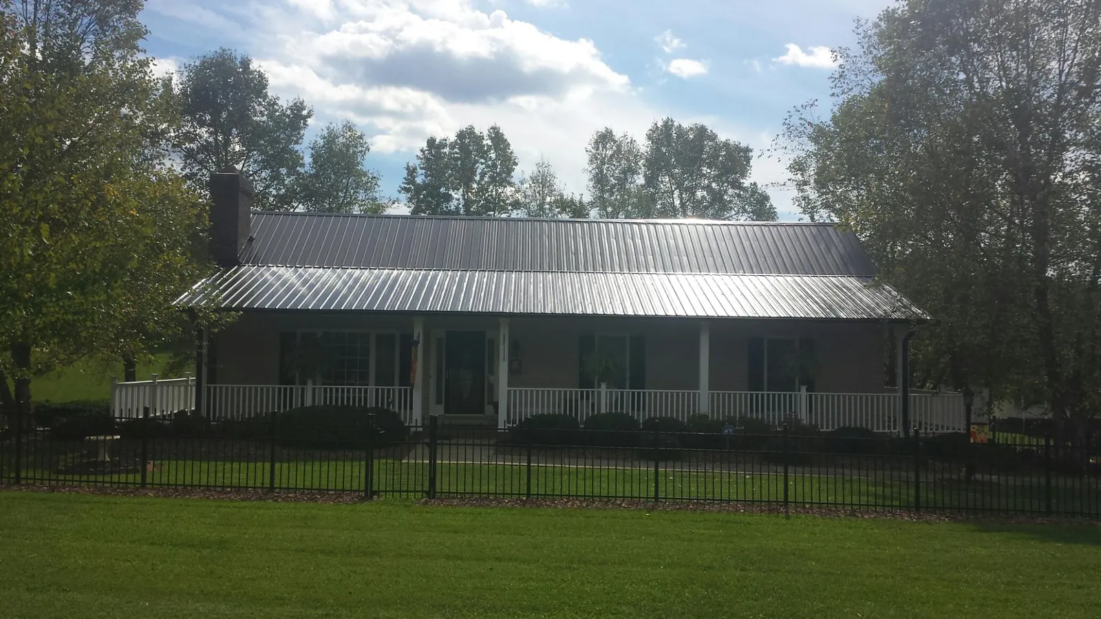 Gray metal roof on a brick ranch with a full width front porch — Gutter Guard Installation work by our crew in Lewes