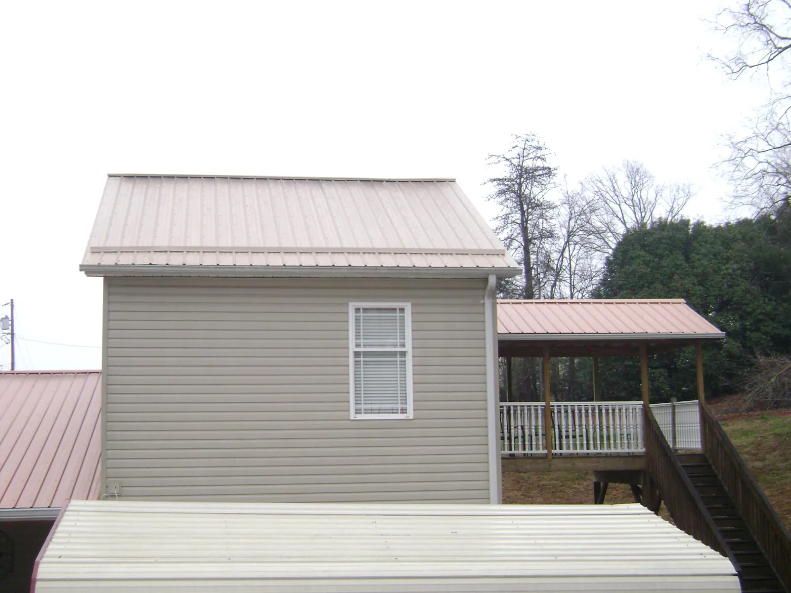 Tan metal roofs on a two story addition and attached porch, from a Roof Replacement job in Lewes