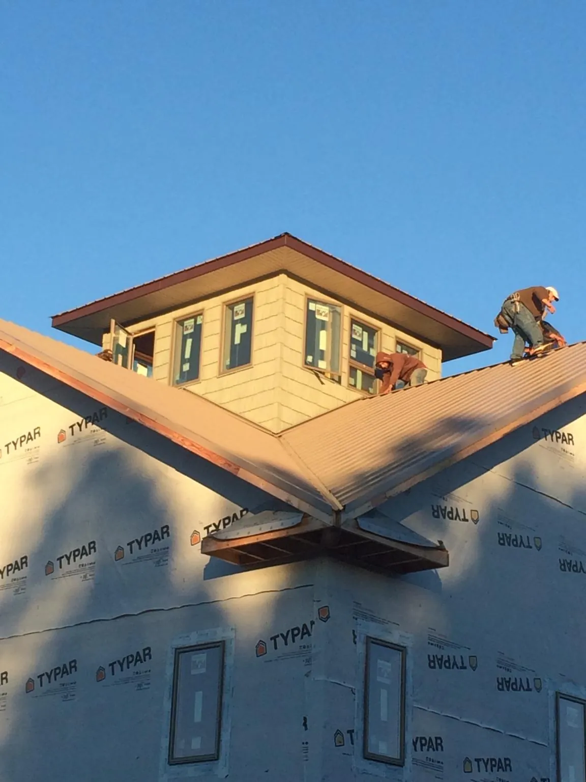Roofers working around a rooftop cupola on a new metal roof at sunset — Roof Waterproofing in Lewes by Roofing Brothers